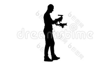 摄影师用相机踩着他的稳定器。 白色背景。 剪影。 侧视图